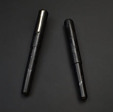 Load image into Gallery viewer, Two Franklin-Christoph Model 31 Black Pen Society fountain pens lie parallel, one with a sleek metal clip.