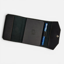 Load image into Gallery viewer, Franklin-Christoph black boot leather A6 snap notebook cover with debossed Celtic logo and a blue marbled pen.