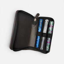 Load image into Gallery viewer, Franklin-Christoph brown leather zippered three pen case with black interior and elastic loops holding blue, clear, and multi-colored pens.
